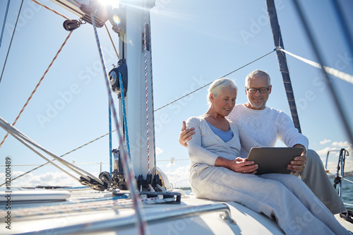 senior couple with tablet pc on sail boat or yacht