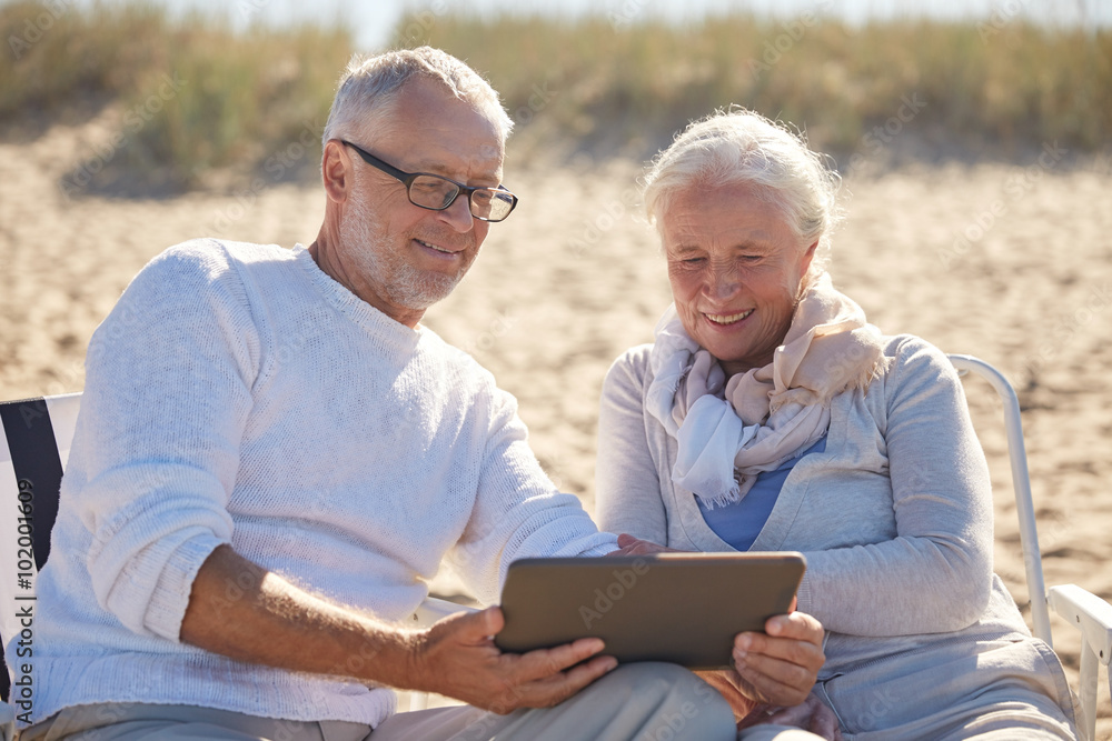 happy senior couple with tablet pc on summer beach happy senior couple with tablet pc on summer beach