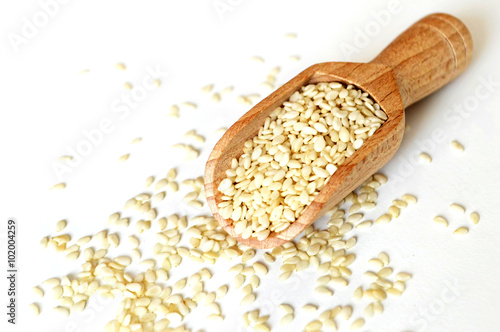 Sesame seeds in wooden scoop, light background