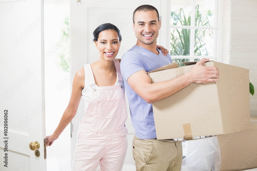 Happy couple entering in their new home with moving box Happy couple entering in their new home with moving box