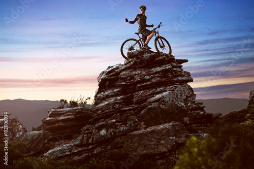 Happy biker on a big rock