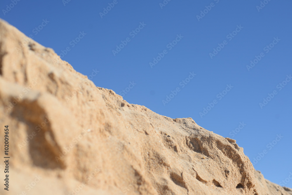 Desert, sandy ground over background of blue sky 