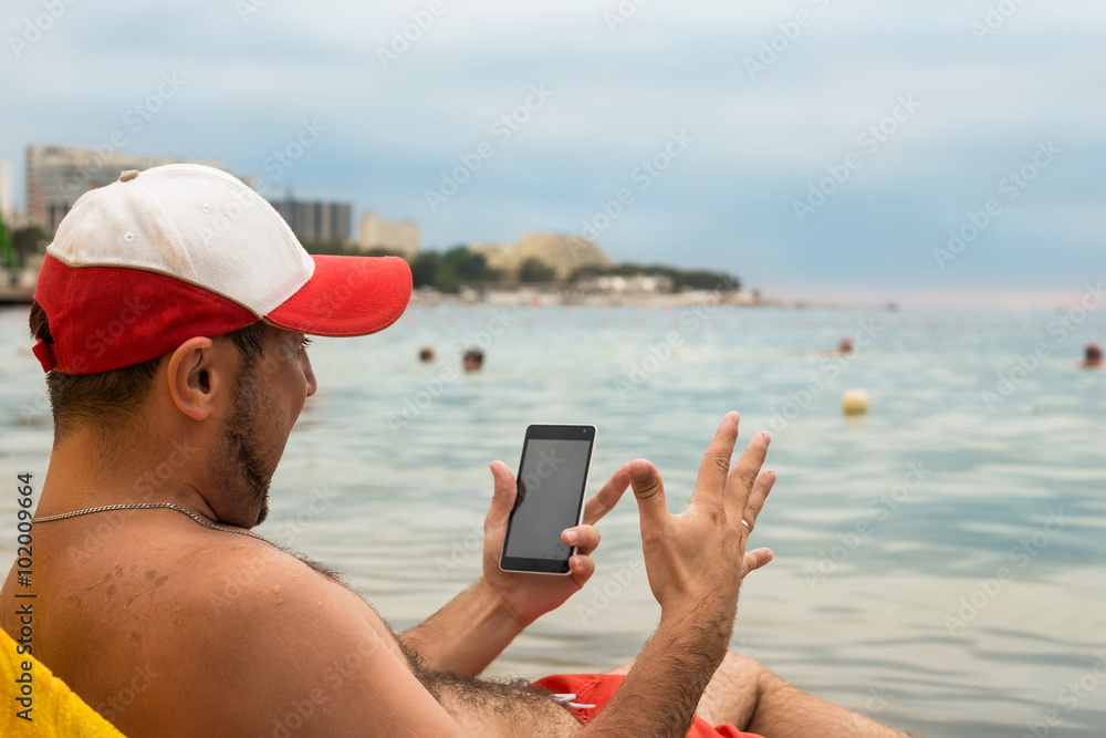 Emotional man with phone in his hand on beach in sea resort