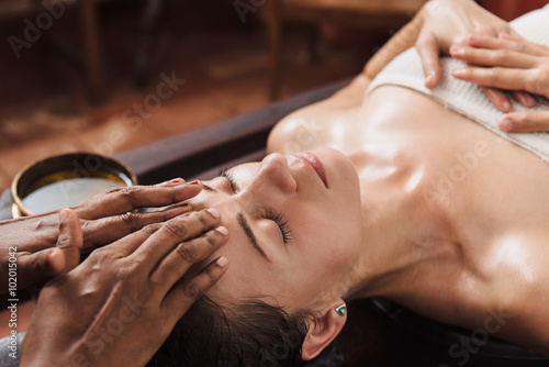 Ayurvedic face massage with oil on the wooden table