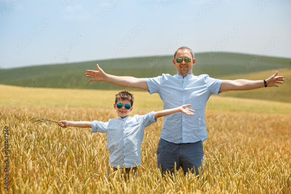 Happy father with little son walking happily in wheat field Happy father with little son walking happily in wheat field
