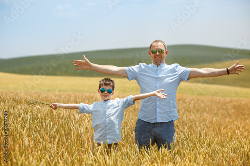 Happy father with little son walking happily in wheat field