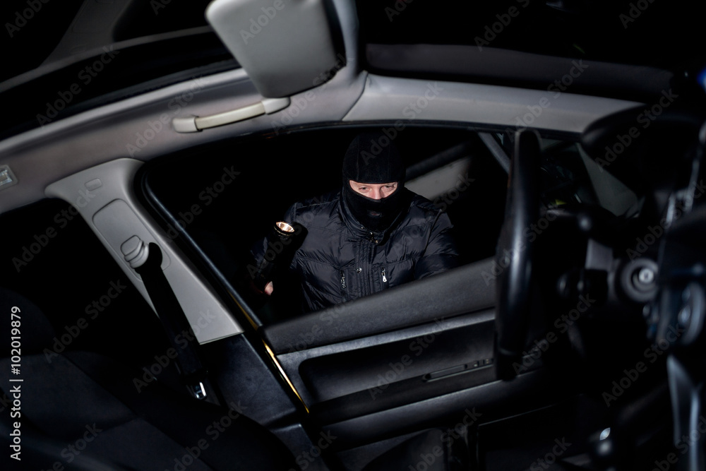 robber with a mask on his face holds the battery and looks what robber with a mask on his face holds the battery and looks what