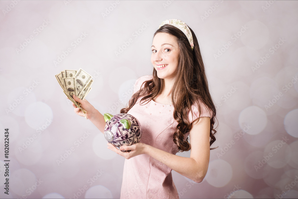 Beautiful young lady holding US banknotes and piggy bank Beautiful young lady holding US banknotes and piggy bank