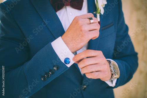 Wedding details, cufflinks, elegant male suit and hands 
