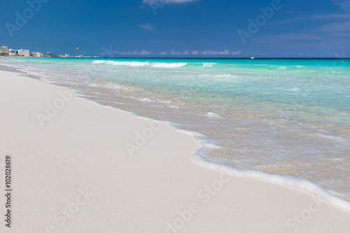 Sea waves with foam on white tropical sandy beach