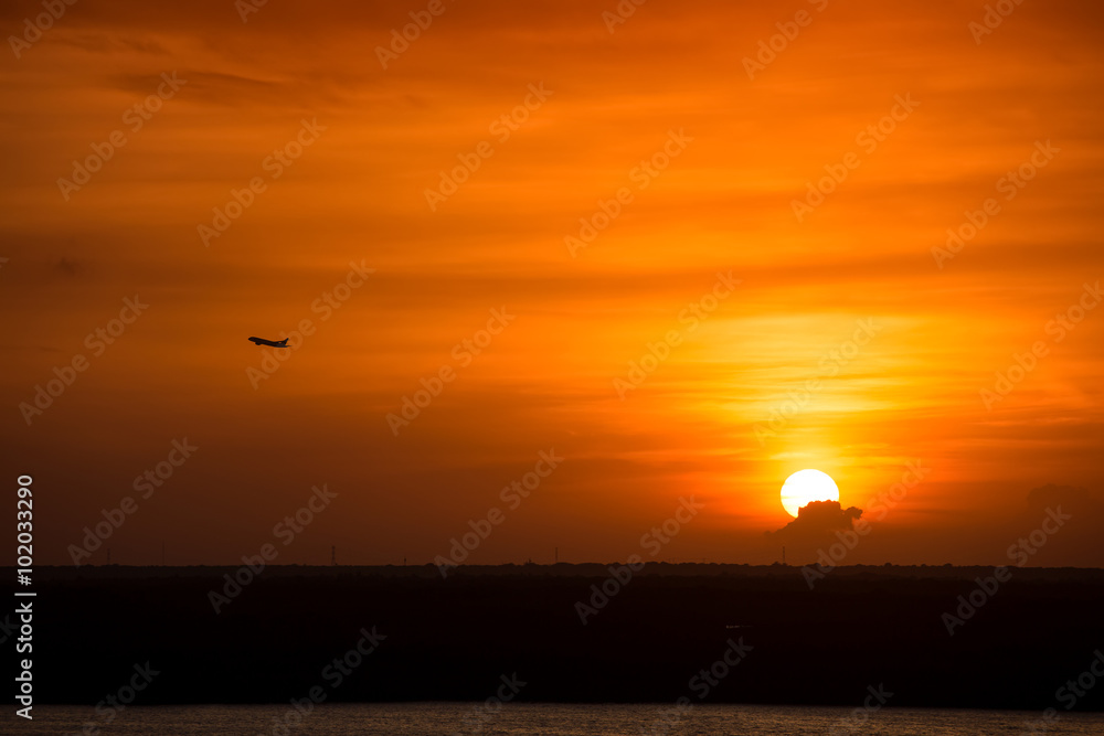 Beautiful yellow sunset with airplane in the sky