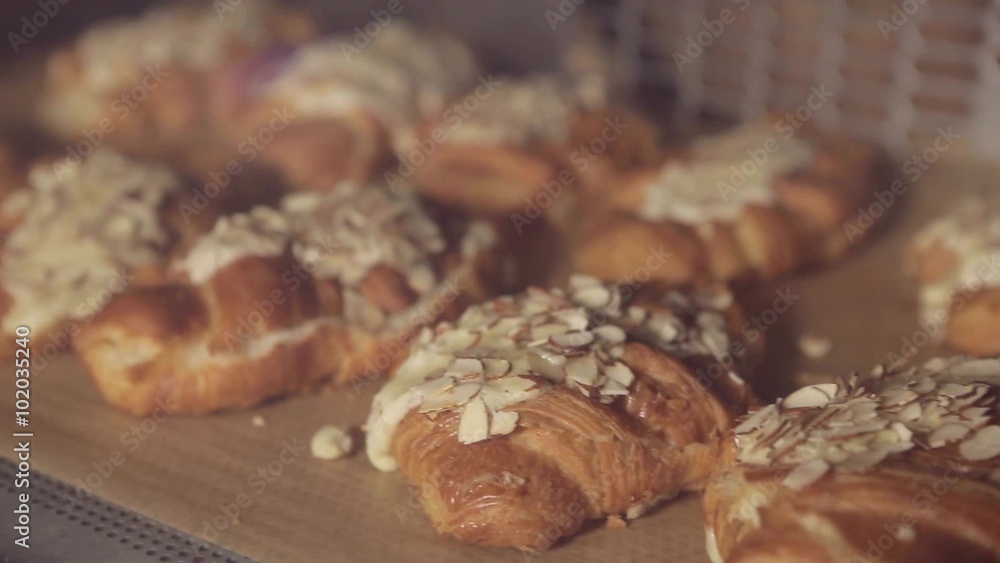 Baking fresh crispy croissants with almonds in the oven in a bakery or grocery store. Farinaceous foods Baking fresh crispy croissants with almonds in the oven in a bakery or grocery store. Farinaceous foods