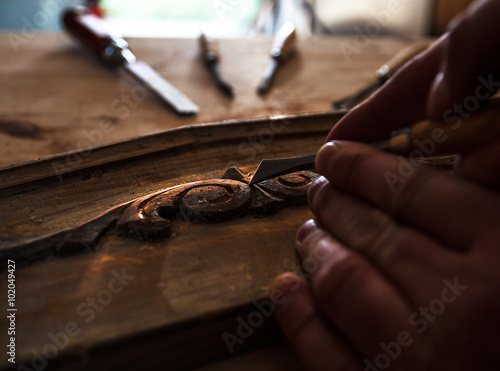 Принти на полотні The hands of an carpenter restoring old furniture with chisel, Close-up