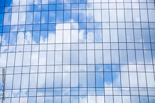 Window of a big office building. Blue sky and fluffy white clouds reflected in  the windows of modern skyscraper.  