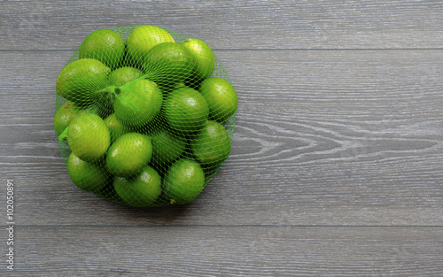 Limes in a bag on wood board background