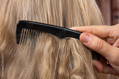 combing long blonde female hair - close up