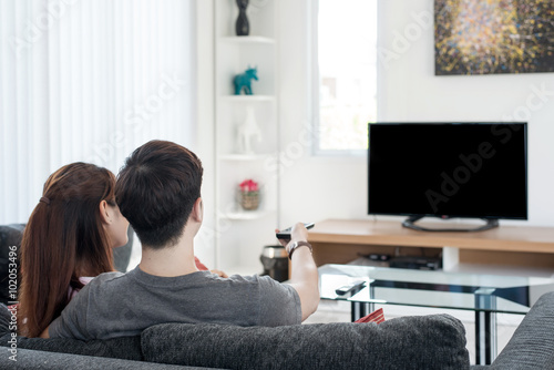 Young Asian couple waching movie on tv at home