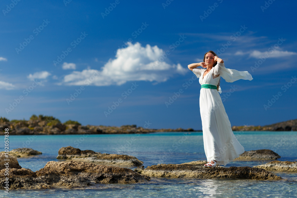 19 okt 2013,  Elafonisi beach, Crete, Greece. Buatiful woman in a white dress on the rocks in the sea