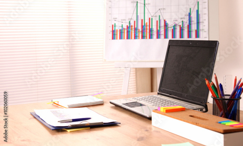 Office table with blank notepad and laptop 