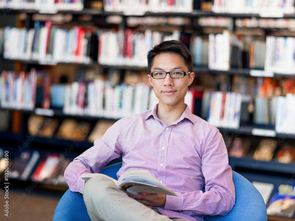 Obraz premium Happy male student holding books at the library