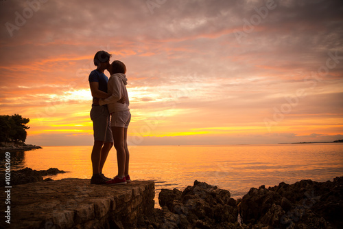 Couple Embracing and Kissing at Sea Sunset