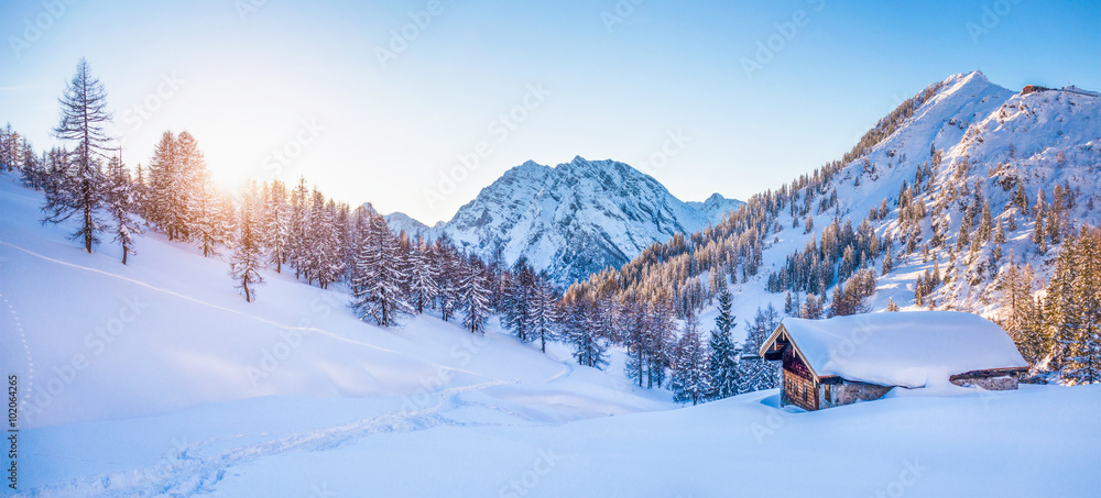 Winter wonderland in the Alps with mountain chalet at sunset