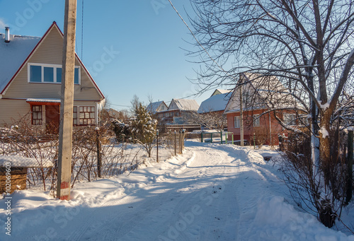 Photo of the winter country road and village. Houses covered with snow. Winter landscape. Russia.