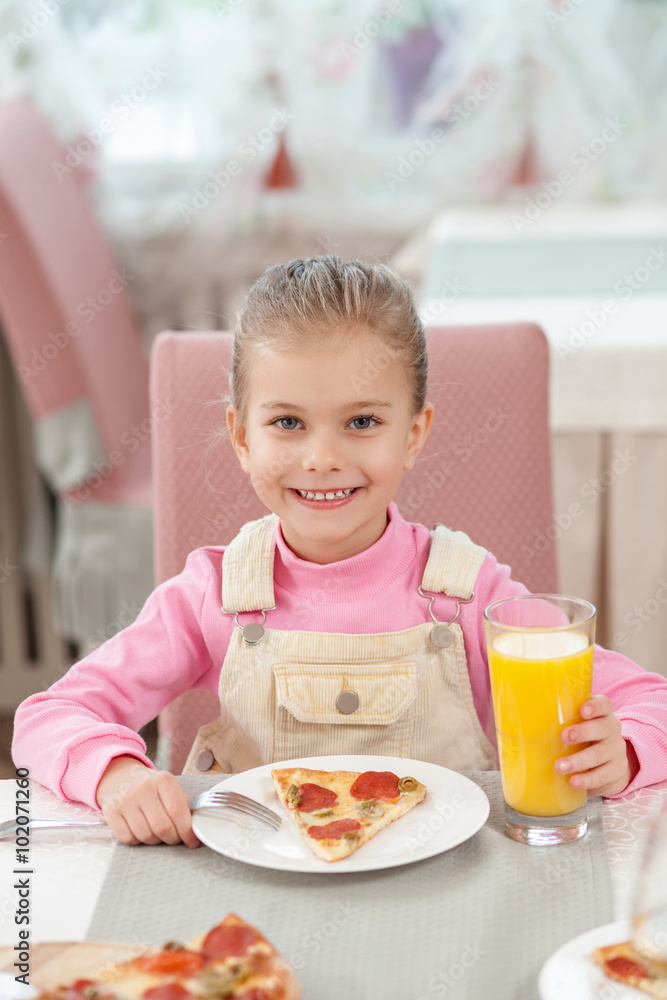 Cute female child has a dinner in cafe