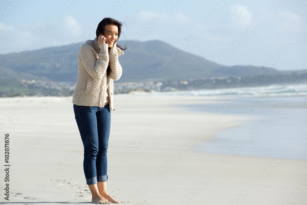 Smiling young woman talking on cell phone at the beach Smiling young woman talking on cell phone at the beach