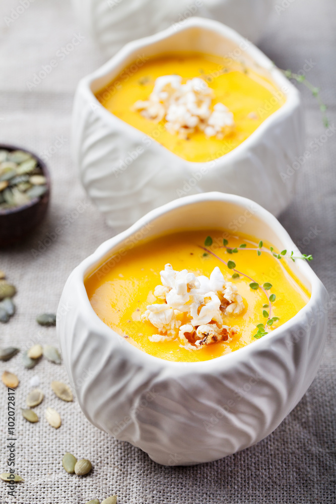 Pumpkin,corn soup with salty popcorn in a white ceramic bowl on a wooden background Pumpkin,corn soup with salty popcorn in a white ceramic bowl on a wooden background
