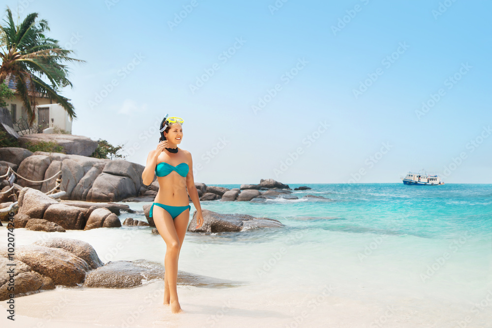 Sexy, young woman in alluring cyan bikini with snorkeling goggles on the beach.