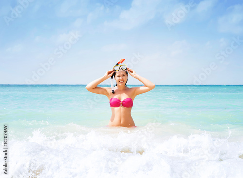 Beautiful, cheerful young woman with diving mask being happy in the wavy water. © Acronym