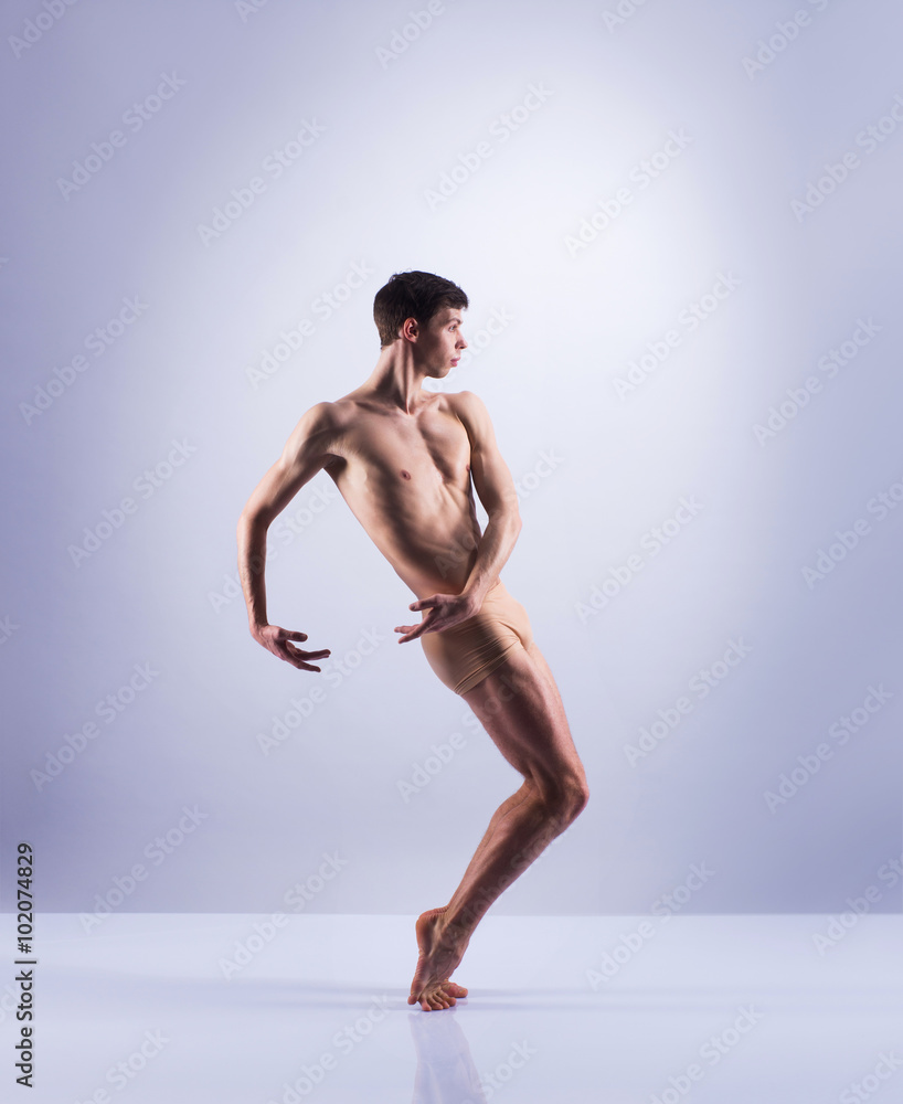 Athletic ballet dancer in a perfect shape performing over the grey background. Athletic ballet dancer in a perfect shape performing over the grey background.