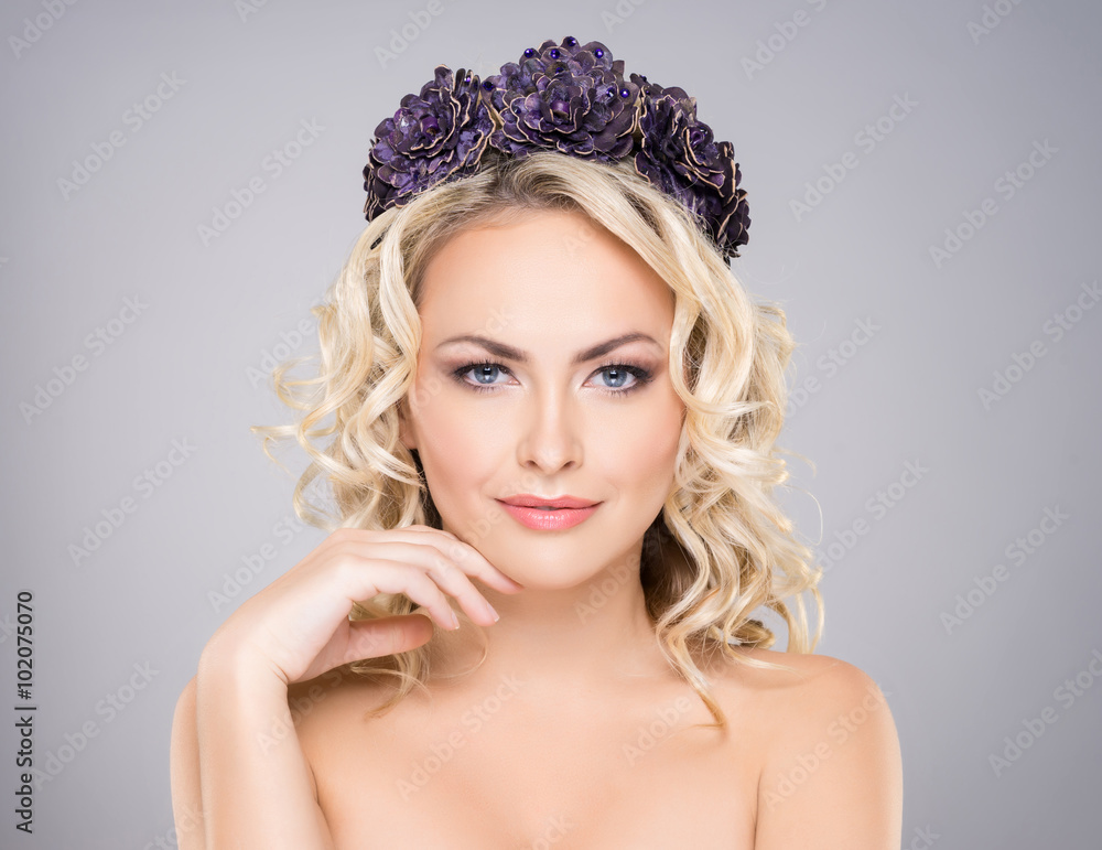 Gorgeous, elegant, sexy woman with bare shoulders wearing purple headband over grey background.