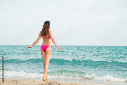 Gentle, sexy lady with hot legs entering wavy sea.