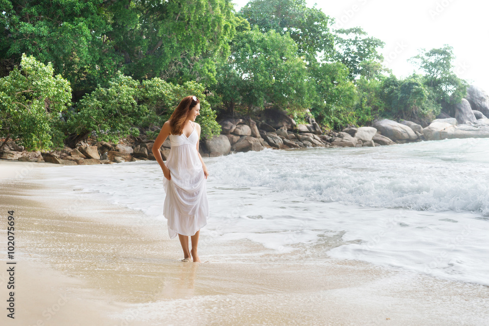 Beautiful, happy girl walking on the seacoast and pulling up her white dress. Beautiful, happy girl walking on the seacoast and pulling up her white dress.