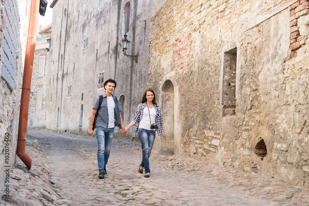 Young travelling couple having a medieval walk on an old street with tile road.