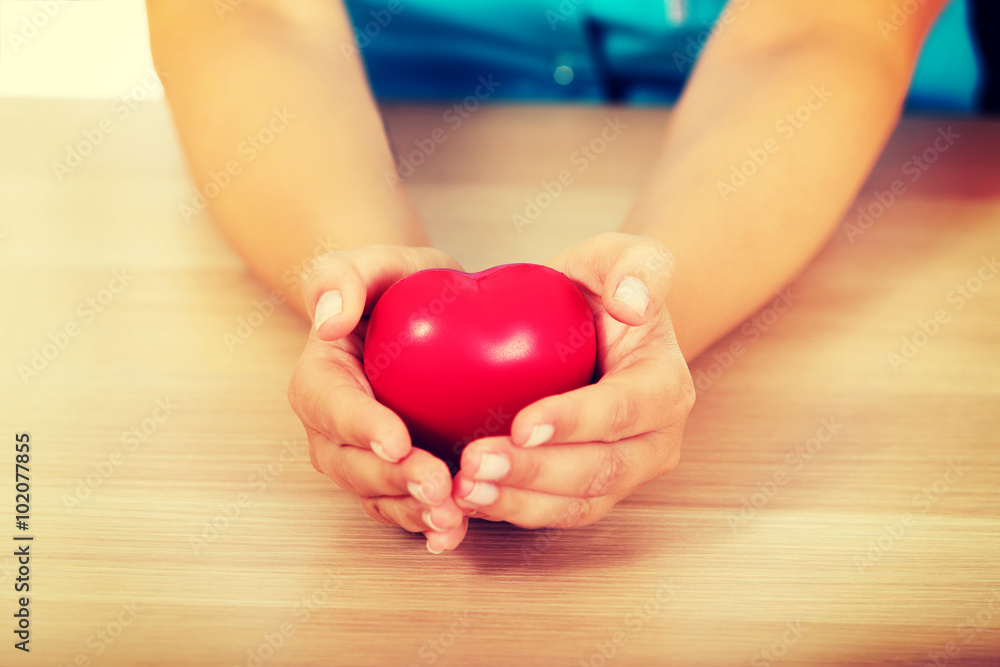 Young female doctor holding toy heart Young female doctor holding toy heart