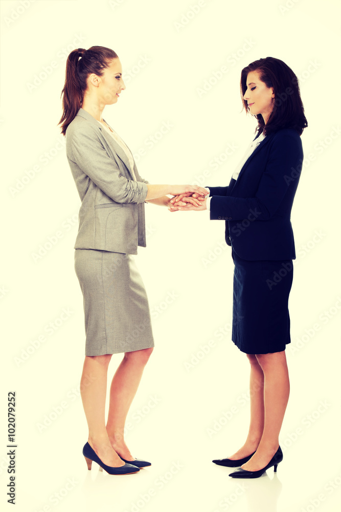Two businesswomen holding their hands together. Two businesswomen holding their hands together.