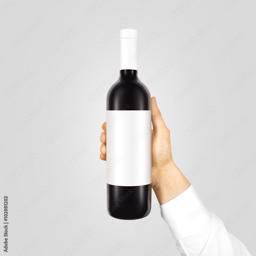 Blank white label mock up on black bottle of red wine in hand isolated.