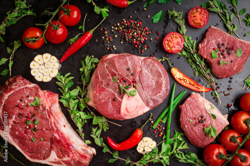Fotografi Raw meat steaks on a dark background ready to roasting