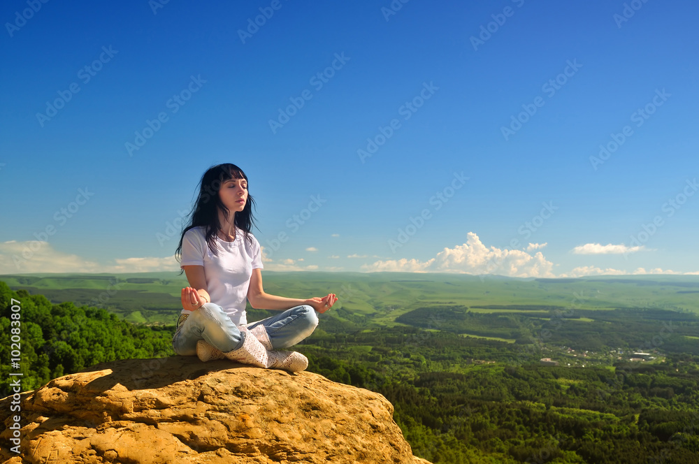Girl sitting in the lotus position on the mountain