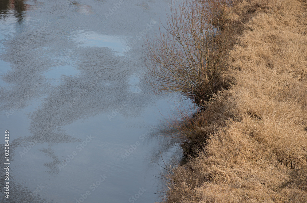 Riverbank with dry brown meadow Riverbank with dry brown meadow