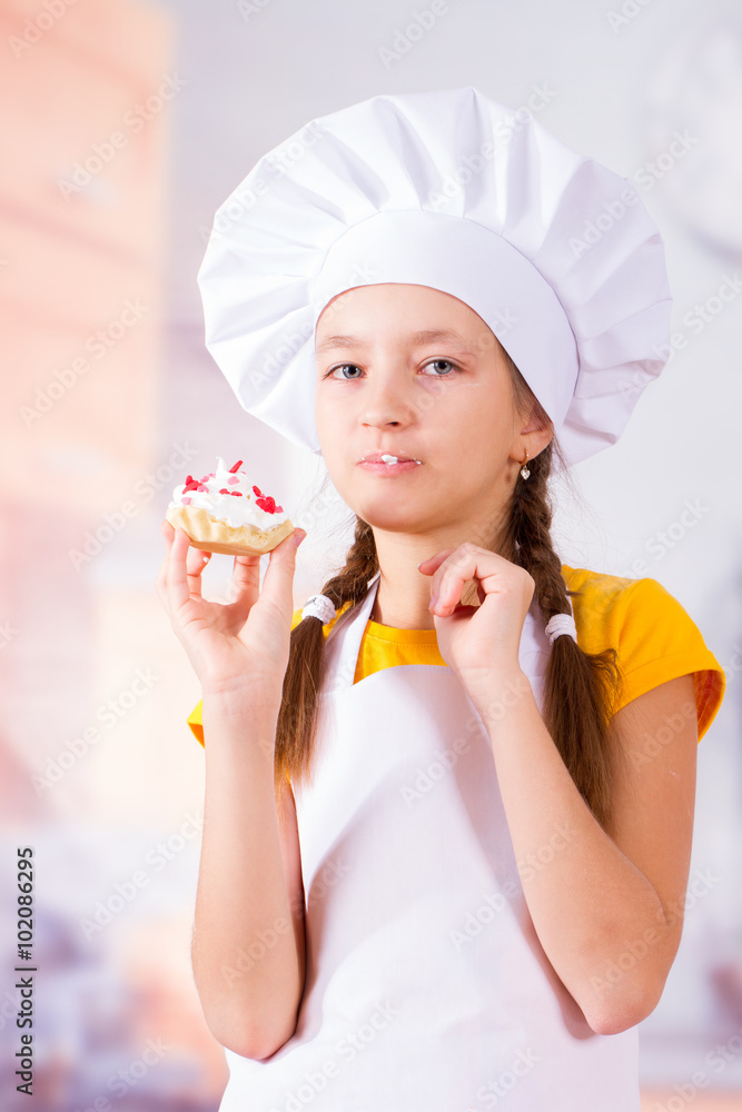 Girl in apron and cap eat delicious cookies Girl in apron and cap eat delicious cookies