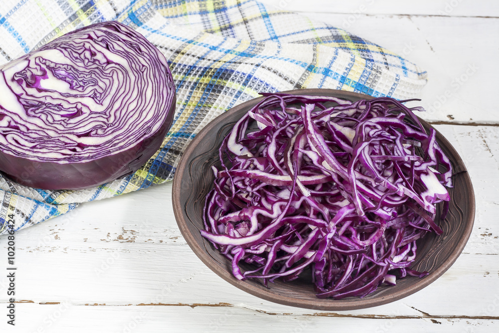 Fototapeta premium Sliced red cabbage in clay bowl on white wooden table