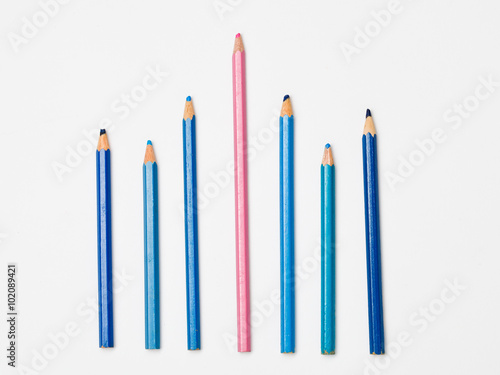 One pink pencil between six blue