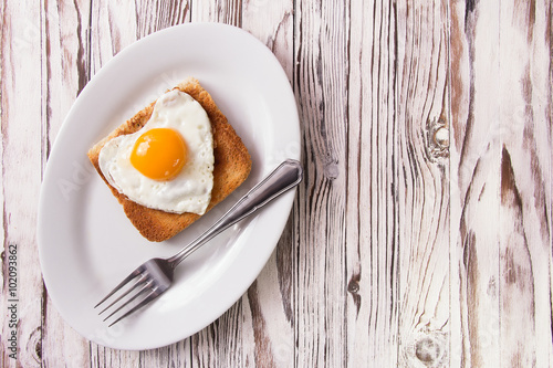 Fried egg on bread for breakfast on plate and rustic table