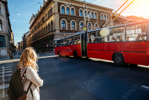 Canvas Print unknown girl with a backpack at the intersection waiting to cross the road and looking at a passing trolleybus, Hungary, Budapest, autumn 2015