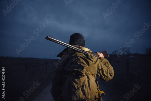 Canvas Print brutal hunter, bearded man in warm hat with a gun in his hand, a knife a backpac