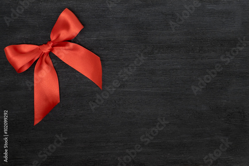 Red satin ribbon with bow isolated over black background.